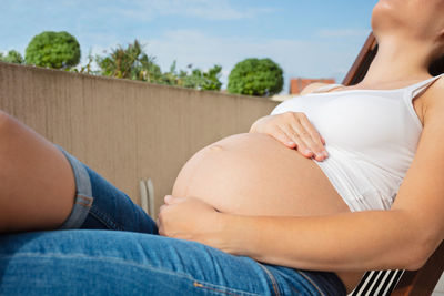 Midsection of woman sitting on retaining wall