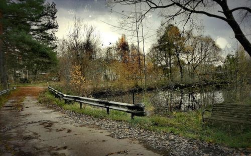 Empty bench in park against sky