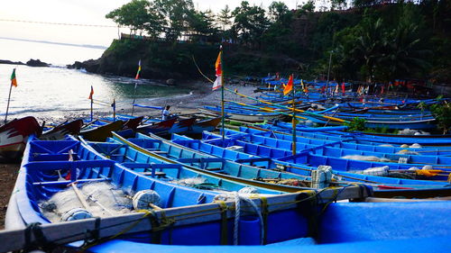 Boats moored at harbor against blue sky