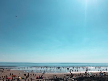 People at beach against blue sky