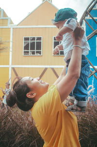 Rear view of mother and daughter in yard against building