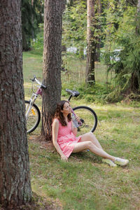 Rear view of woman sitting on tree trunk