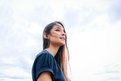 Portrait of smiling young woman against sky