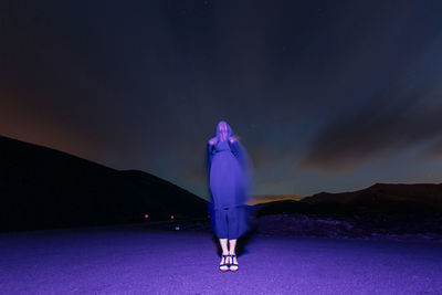 Low angle view of man standing by sea against sky at night