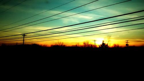 Silhouette of electricity pylon at sunset