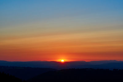 Scenic view of silhouette mountains against romantic sky at sunset