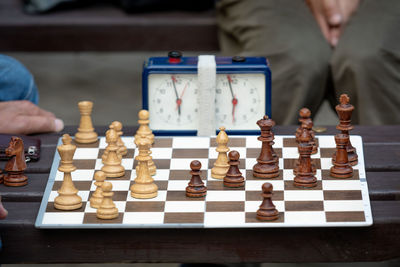 Midsection of men playing chess by clock on table