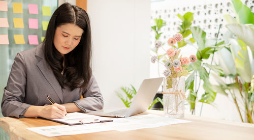 Portrait of young woman using laptop at office