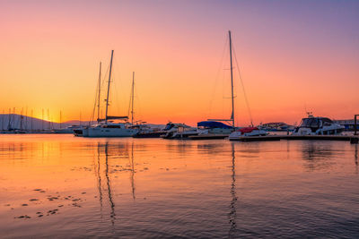 Sailboats moored at harbor during sunset