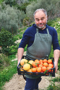 Portrait of man holding fruits in basket