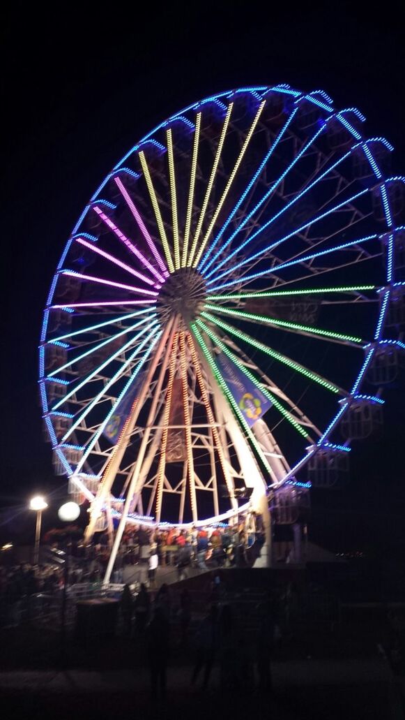 illuminated, night, arts culture and entertainment, amusement park ride, amusement park, ferris wheel, multi colored, low angle view, sky, lighting equipment, circle, motion, built structure, celebration, outdoors, glowing, clear sky, architecture, long exposure, decoration