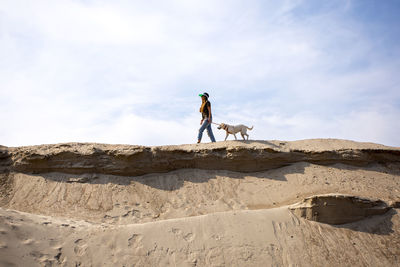 Rear view of man standing on rock against sky