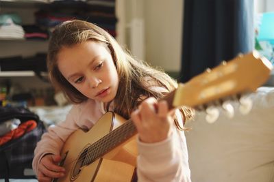 Close-up of girl playing guitar at home