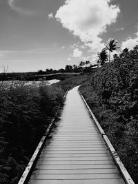 Boardwalk on field against sky