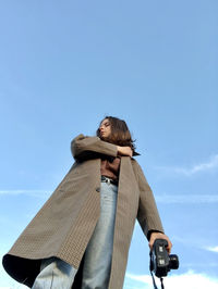 Low angle view of woman against blue sky