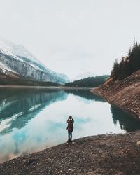 Rear view of man standing by oeschinen lake against clear sky