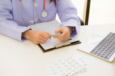 Midsection of man using mobile phone on table