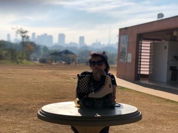 Woman sitting on building against sky