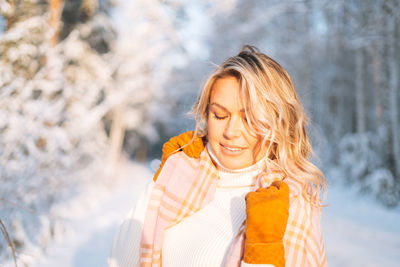 Portrait of young woman standing against trees