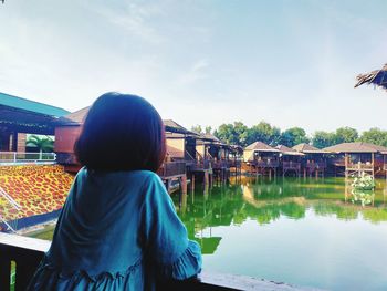 Rear view of boy looking at lake against sky