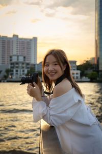 Portrait of young woman holding camera