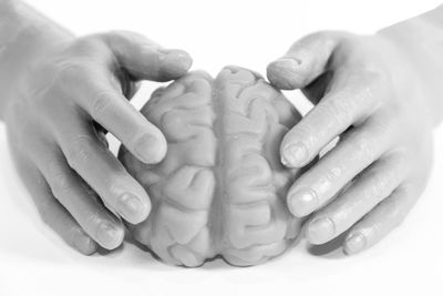 Close-up of hands holding ice cream over white background