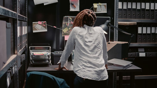 Rear view of young woman standing in library