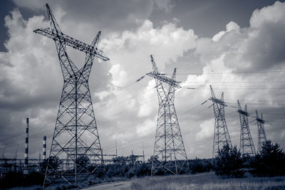 Low angle view of electric pylon on field against sky