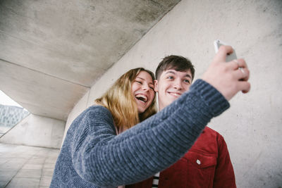 Smiling young woman using smart phone while standing outdoors