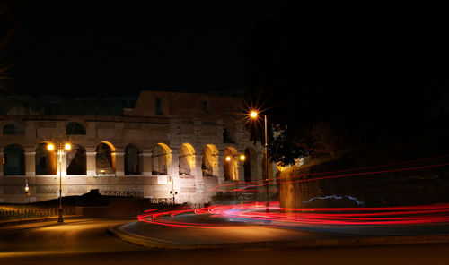 Light trails on road against illuminated city at night