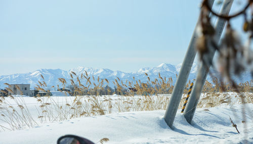 Snow covered land and mountains against clear sky