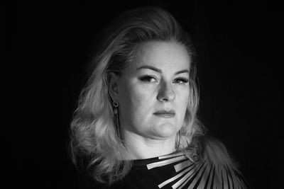 Portrait of young woman against black background