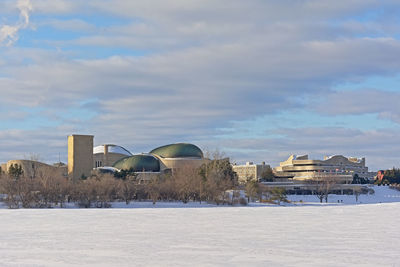 Houses by buildings against sky during winter