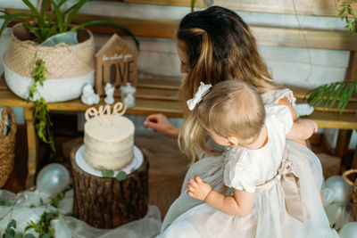 High angle view of mother with daughter looking at cake