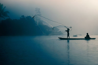 Silhouette fisherman fishing in lake