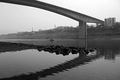 Bridge over river in city against clear sky