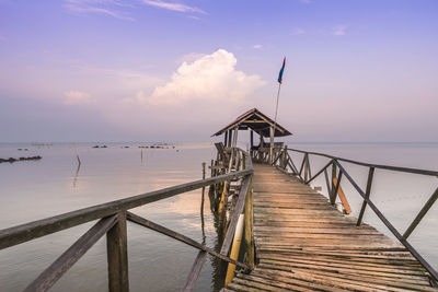 Pier over sea against sky during sunset