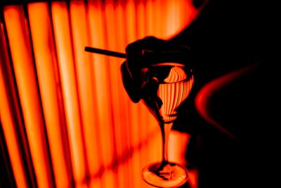Cropped image of person holding wineglass and cigarette at nightclub in dark