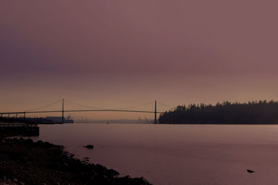 Suspension bridge over sea during sunset