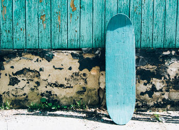 Green wooden skateboard on deteriorated wall on a sunny day. skateboarding background