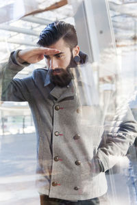 Side view of young man looking through window