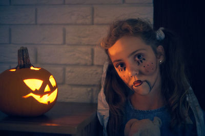 Cute girl wearing costume standing by pumpkin during halloween