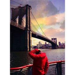 Rear view of suspension bridge over river against sky