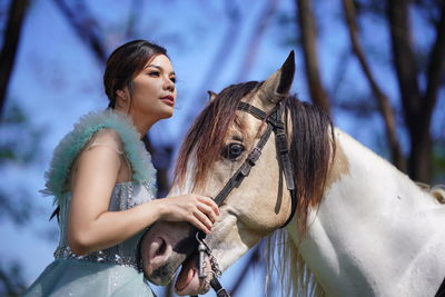 Portrait of a beautiful woman with a horse in the forest background.