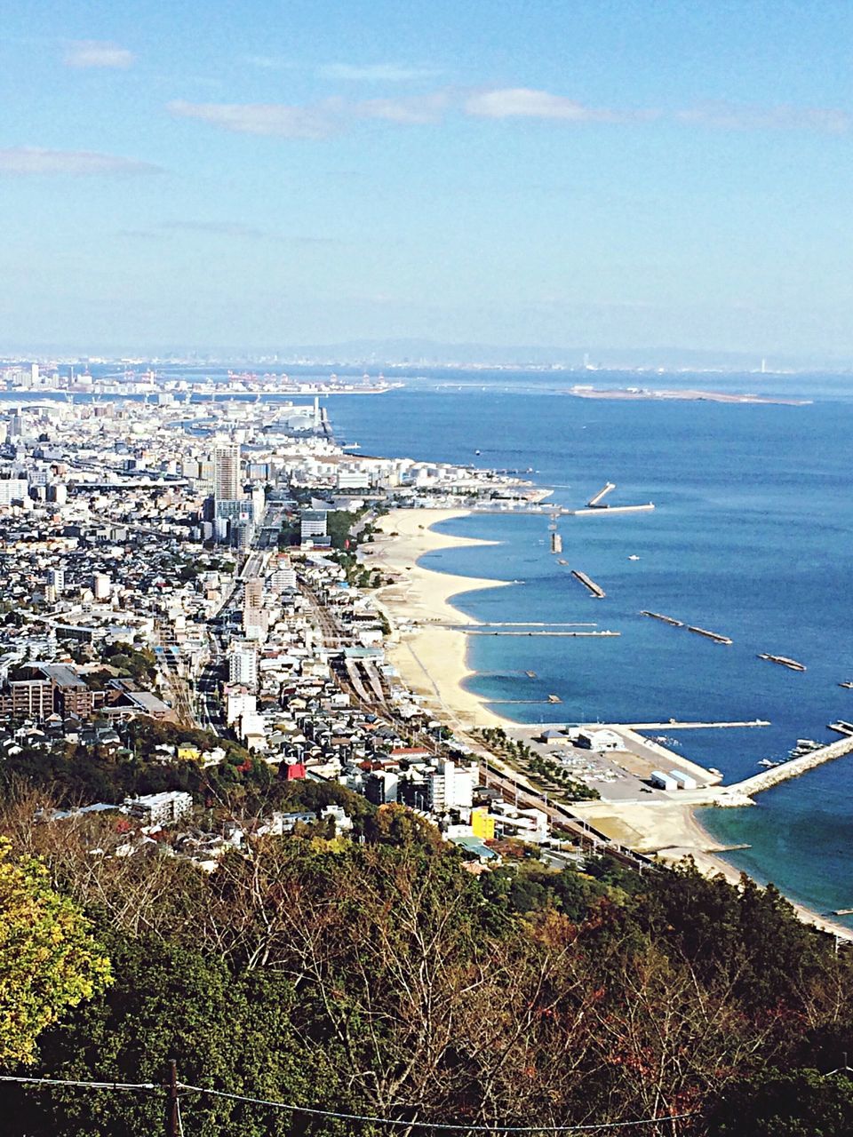 sea, water, high angle view, building exterior, horizon over water, cityscape, city, built structure, architecture, sky, beach, blue, crowded, residential district, coastline, shore, nature, scenics, day, tree