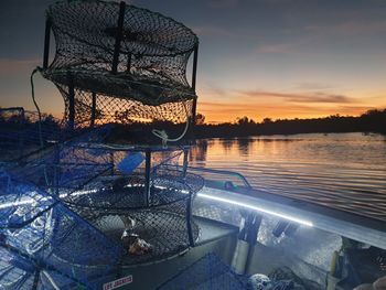 Fishing net in lake against sky during sunset