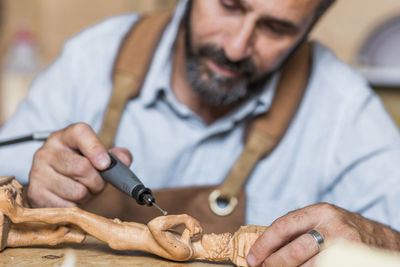 Carpenter carving on figurine in workshop
