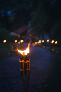 Close-up of lit torch on footpath at dusk