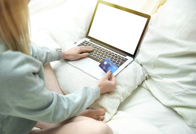 High angle view of woman using mobile phone on bed