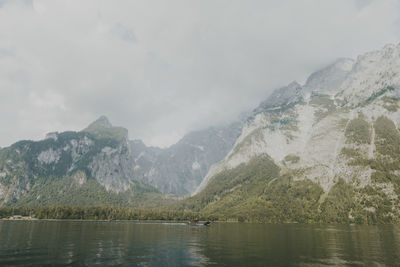 Trees with mountain range in background against cloudy sky